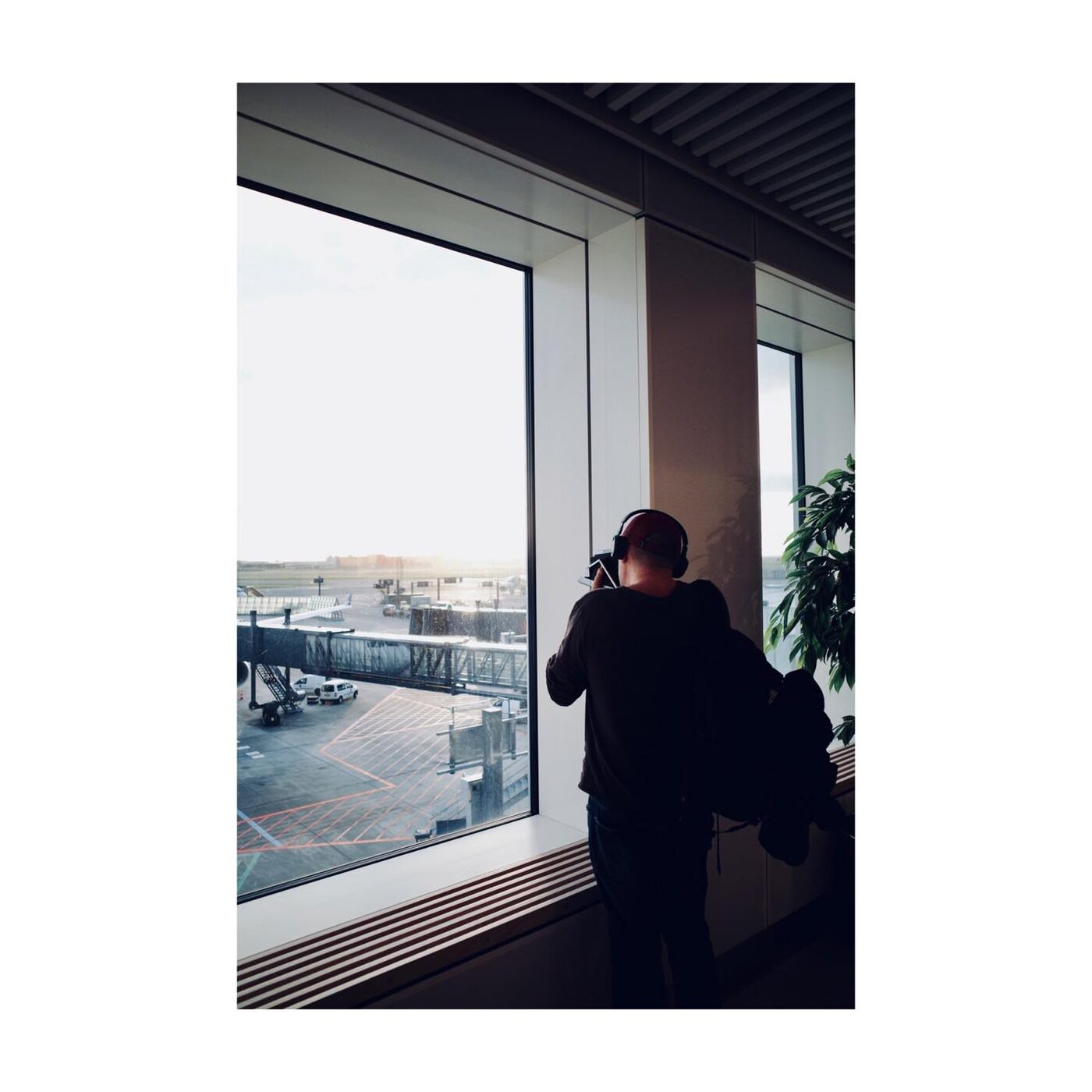 A photographer looking out a window, camera in hand, silhouetted against the light