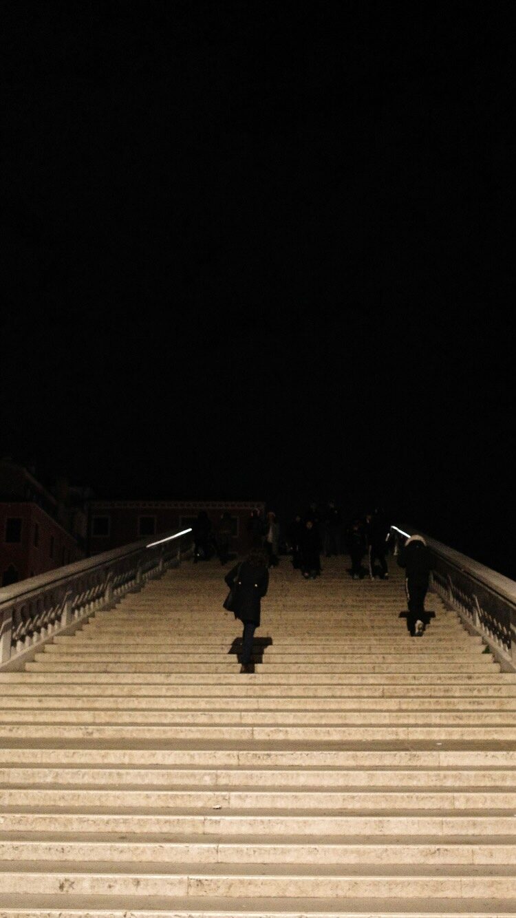 A dark stairwell glowing at night with distant figures