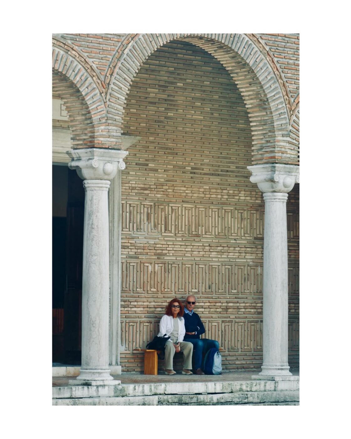 A person reading alone in a brick archway