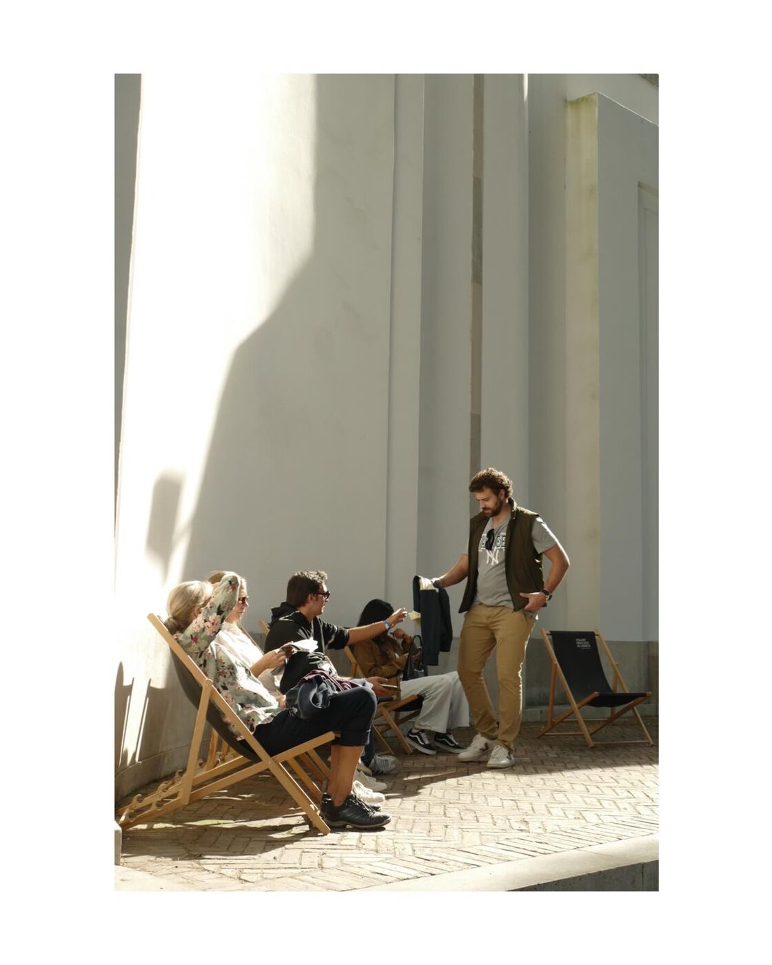 A man with headphones leaning against a wall