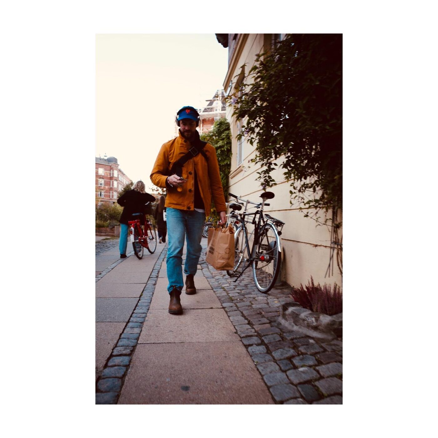 A person walking a bike down a sidewalk in autumn