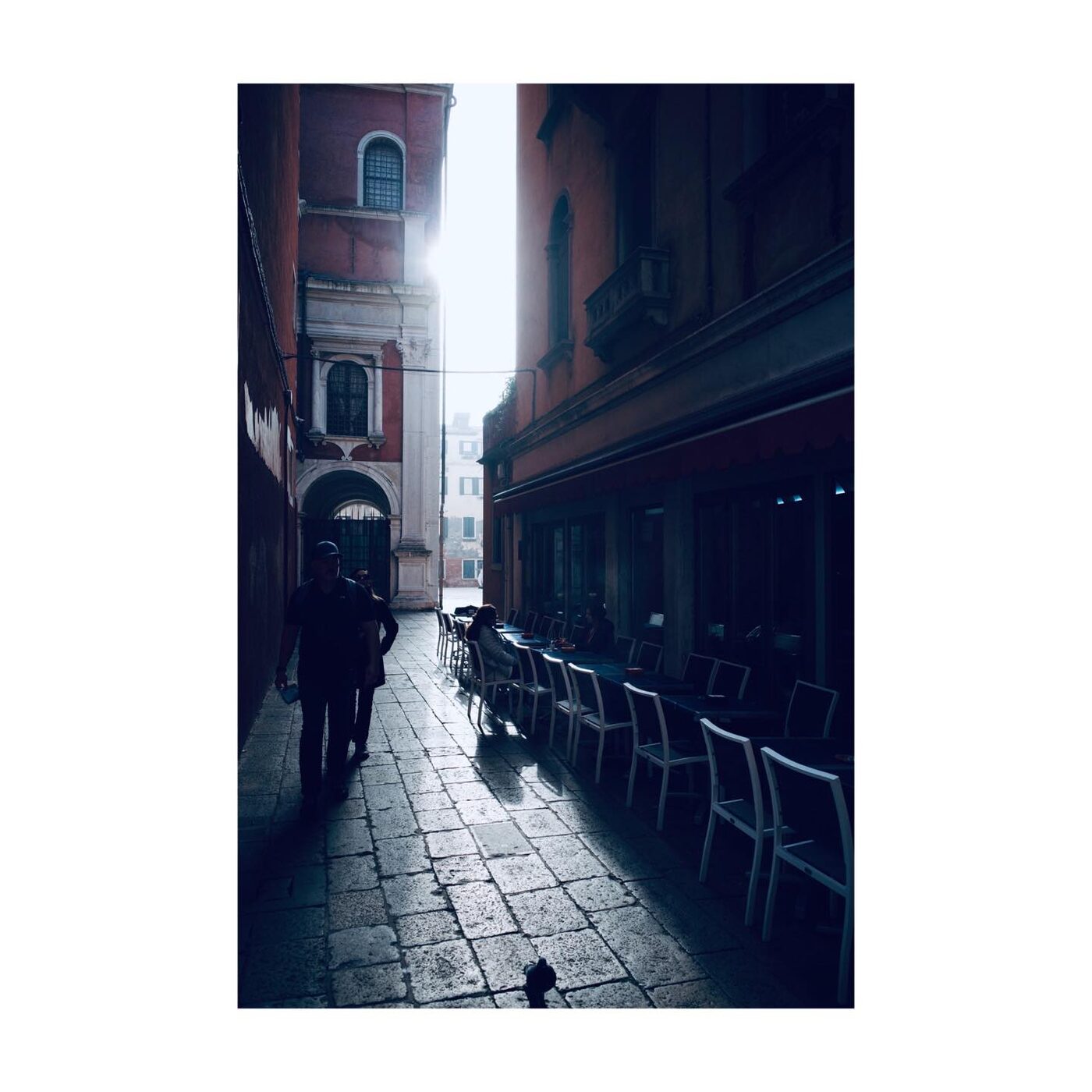 A single figure walking past a glowing doorway at night